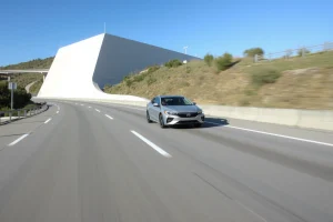 A modern, reliable car driving smoothly on a clean, well-maintained highway under a clear blue sky, with visible road markings, gentle curves, and a sense of calm motion — emphasizing stability and safety. The vehicle is centered, slightly angled forward, with soft natural lighting highlighting its sleek design. No people, text, logos, or license plates visible.
