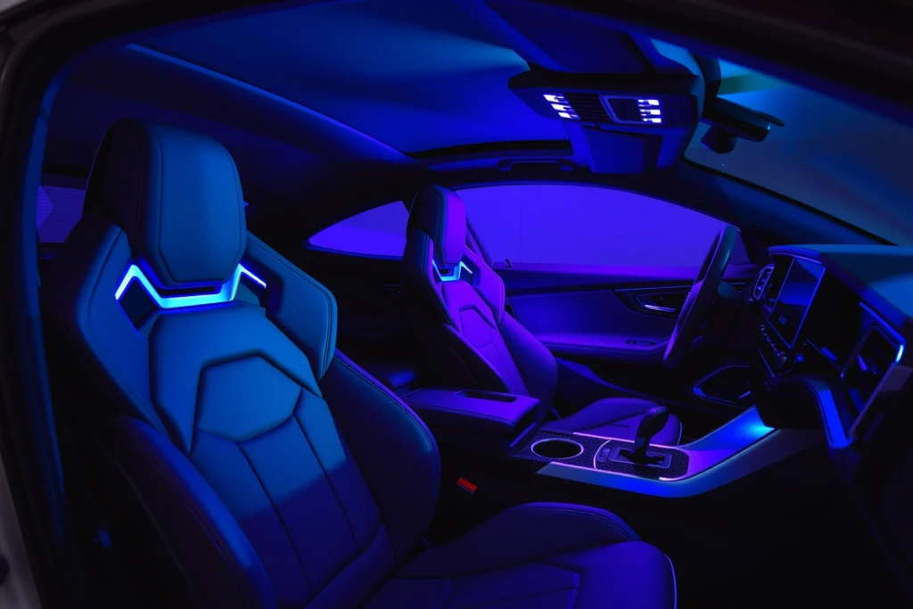 A modern, stylish car interior with sleek leather seats, ambient LED lighting in blue and purple tones, a minimalist digital dashboard, and a high-end steering wheel with carbon fiber accents, viewed from a slightly elevated angle to emphasize luxury and design