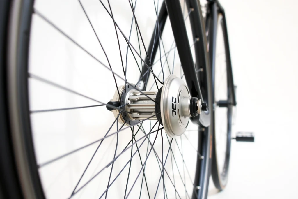 A close-up of a high-quality bicycle wheel with a sleek carbon fiber rim, silver hub, and black spokes, mounted on a clean white background with soft natural lighting, emphasizing texture and precision engineering