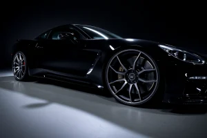 A set of exclusive, high-end custom wheels designed for luxury and performance vehicles, displayed on a sleek black sports car under dramatic studio lighting, with polished chrome and matte black finishes, intricate spoke designs, and subtle carbon fiber accents, emphasizing craftsmanship and exclusivity