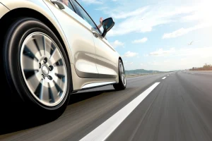 A high-quality, detailed illustration of premium car wheels designed for long-distance travel, showing durable alloy rims with aerodynamic design, mounted on a sedan driving on a smooth highway under clear skies, with subtle motion blur to convey speed and comfort, emphasizing reliability and endurance for road trips