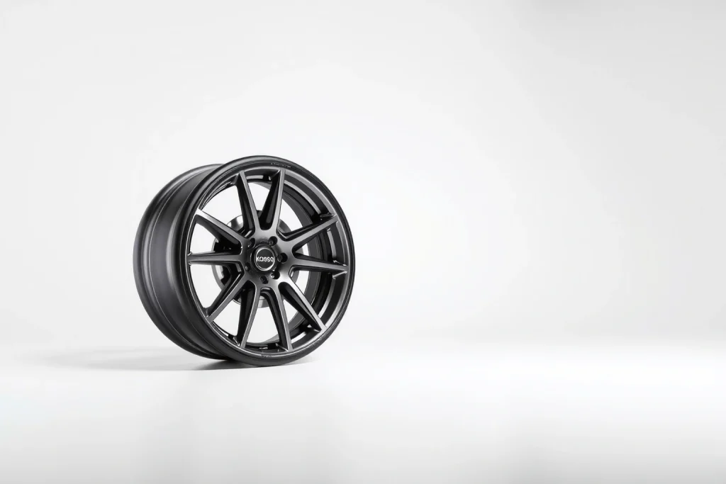 A modern, sleek car wheel with the 'koleso-bestune' branding, displayed on a clean white background with soft studio lighting, emphasizing its aerodynamic design, high-quality alloy material, and precision engineering; subtle reflections and depth to highlight craftsmanship, no text or logos visible on the wheel itself