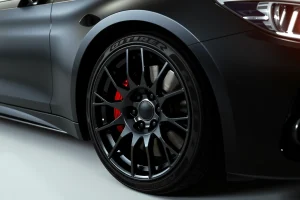 A set of high-end, glossy black alloy wheels with intricate multi-spoke design, mounted on a sleek luxury sedan under soft studio lighting, emphasizing reflective surfaces and precision engineering, no text or logos visible