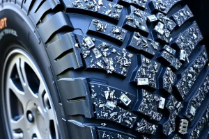 A close-up view of a vehicle tire with detailed wheel rims designed for improved traction, showing deep treads and specialized rubber compounds for better grip on various surfaces