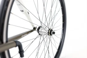 A close-up of a high-quality bicycle wheel with a sleek carbon fiber rim, precision spokes, and a modern hub, displayed on a clean white background with soft natural lighting to highlight texture and detail