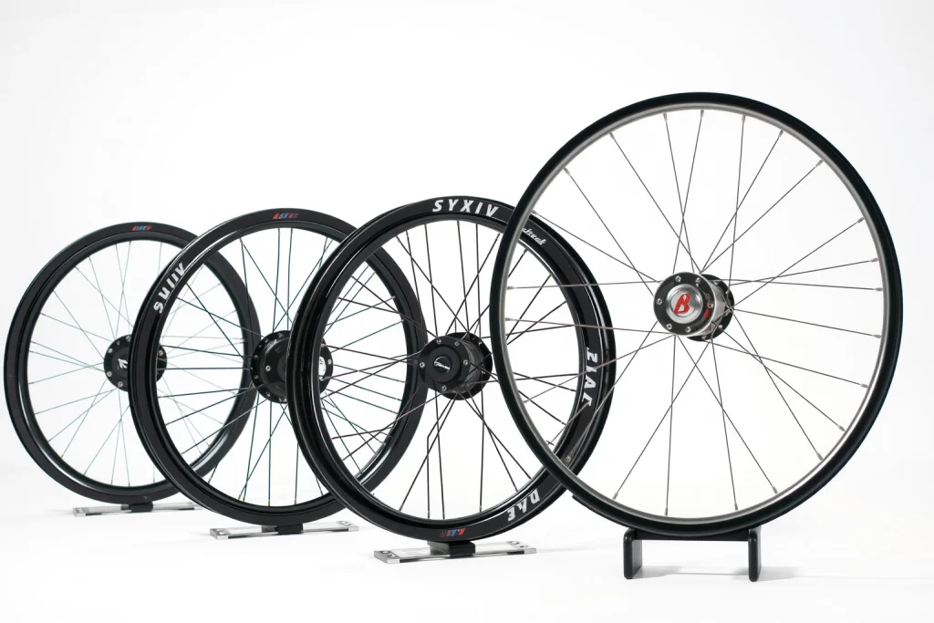 A set of lightweight and durable wheels made of carbon fiber and alloy, displayed on a clean white background with soft lighting, showing their sleek design, thin spokes, and robust hub construction, emphasizing strength-to-weight ratio and modern engineering